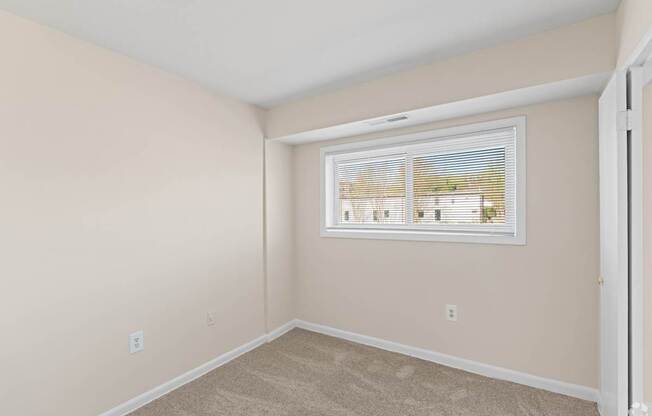 A room with a window showing a view of a house.
