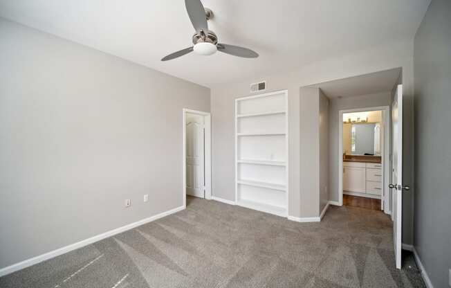 an empty living room with a ceiling fan and a closet