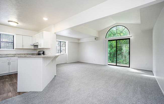 An end style living room with a cathedral ceiling and sliding glass doors to a balcony at Foxwood and The Hermitage in Portage, MI