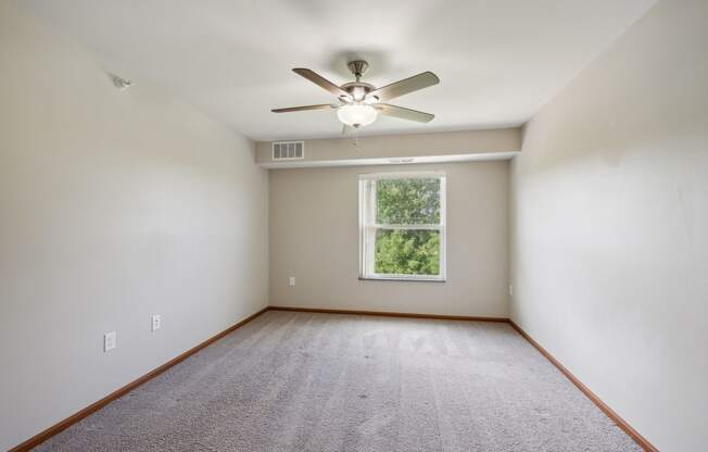 an empty room with a ceiling fan and a window