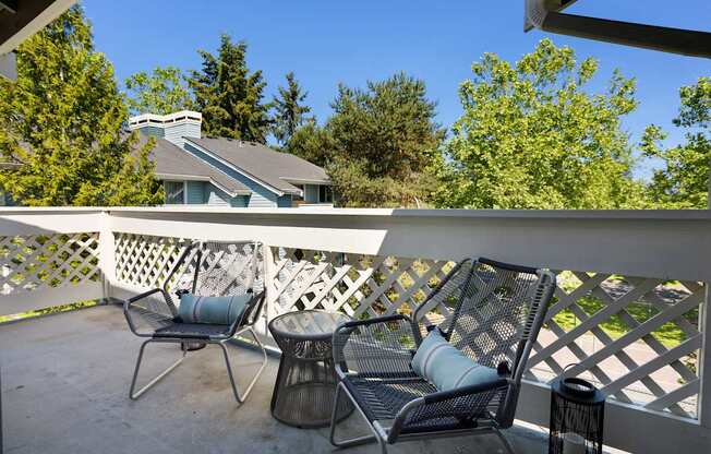 A patio with a white railing and two chairs.