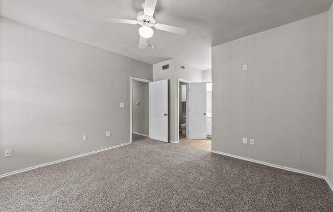 A room with a ceiling fan and carpeted floor.