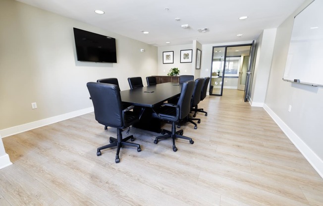 a conference room with a long table and chairs and a tv