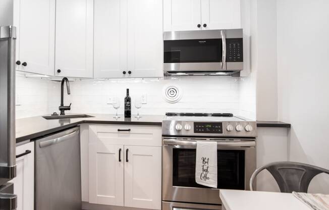 a white kitchen with stainless steel appliances and white cabinets