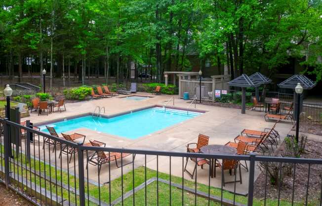 a swimming pool with chairs around it and a patio with trees at The Summit Apartments, Memphis, Tennessee