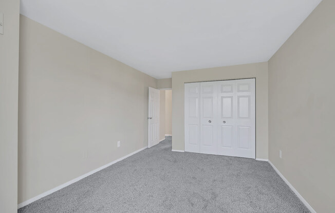 an empty bedroom with a white door and carpet