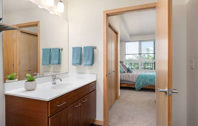 a bathroom with a mirror and a sink and a door to a bedroom