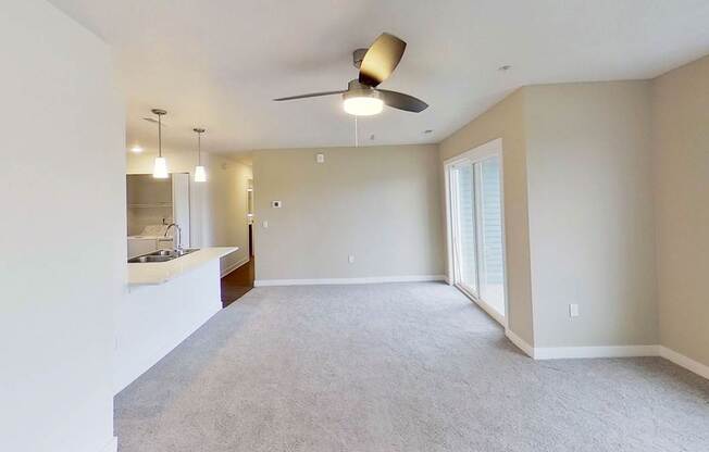 A spacious dining room with a ceiling fan and carpeted floor at Meadowbrooke Apartment Homes in Kentwood, MI 49512