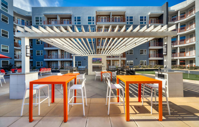 an outdoor patio with orange tables and white stools at The Rey Downtown, Arizona