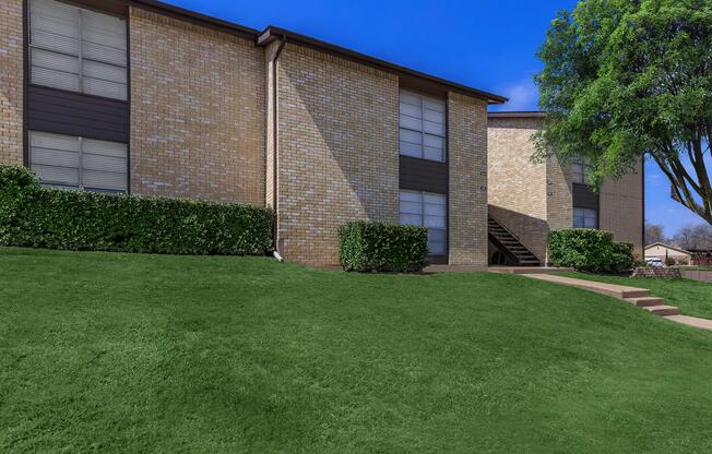 a house with a lawn in front of a brick building