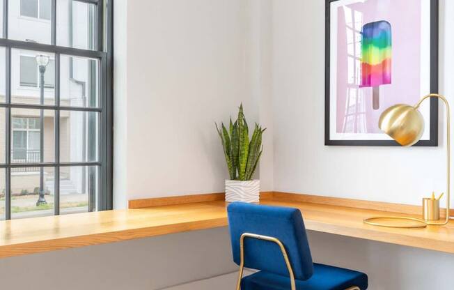 a desk with a chair and a potted plant in a room with a window