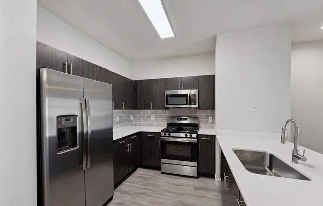 A modern kitchen with a stainless steel refrigerator and a stove top oven.