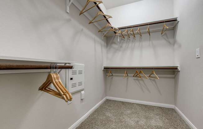 A white closet with two shelves and hangers.