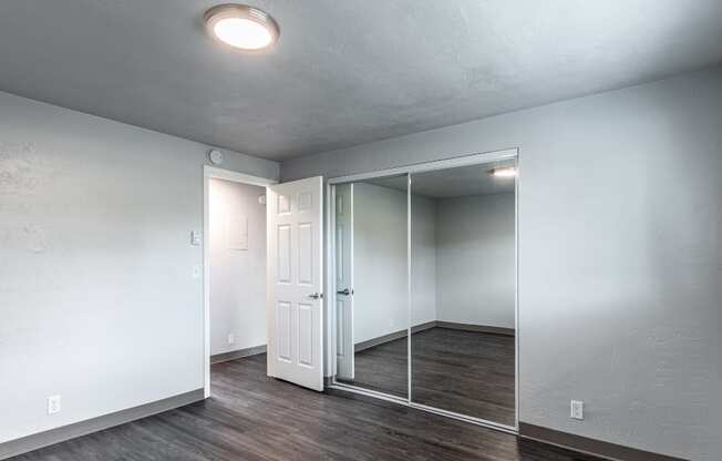 an empty room with white walls and a mirrored closet