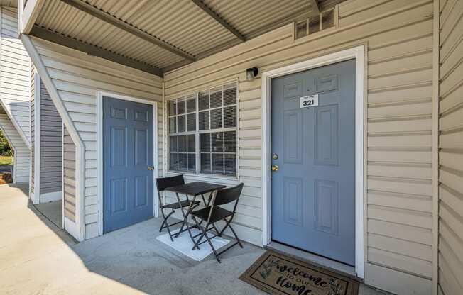 a patio with a table and chairs in front of a blue door