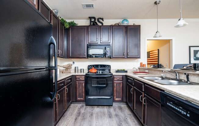 Kitchen with sleek black appliances and dark wood cabinetry at Riverstone apartments for rent in Macon, GA