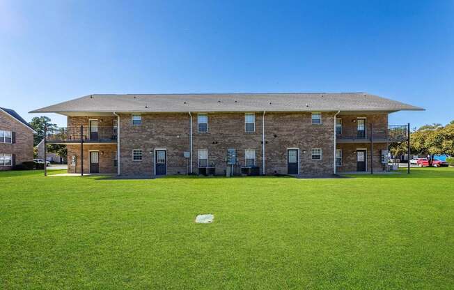 A large building with a flat roof and a green lawn in front.