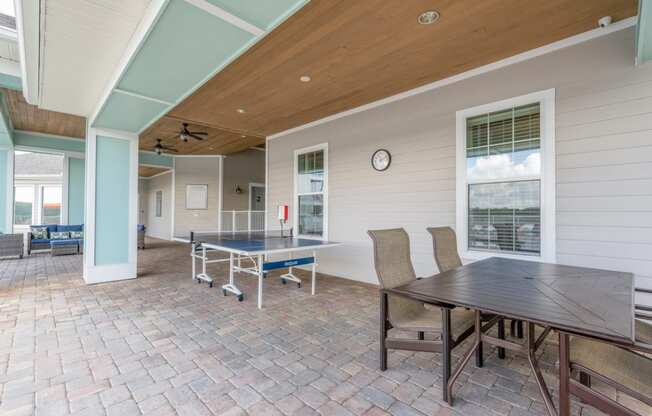 a patio with a ping pong table and a dining table