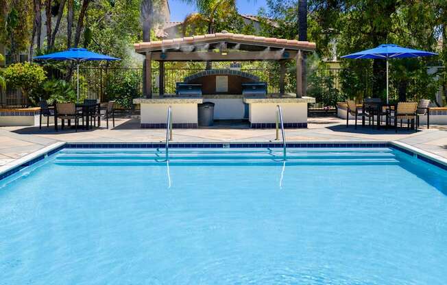 A pool with a bar and chairs around it.