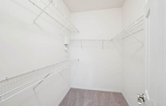 A walk-in closet with white walls and shelving.