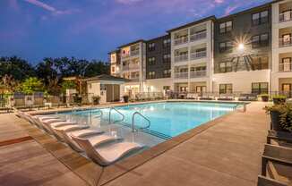 a swimming pool with chaise lounge chairs and a building in the background