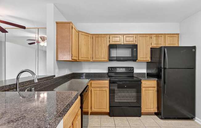 A kitchen with black appliances and wooden cabinets.