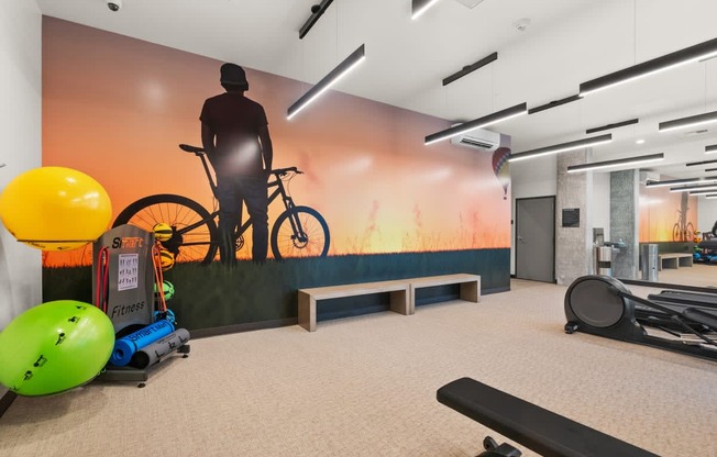 A man is standing next to a bicycle in a room with exercise equipment.