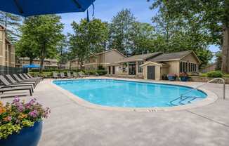A swimming pool surrounded by lounge chairs and trees.