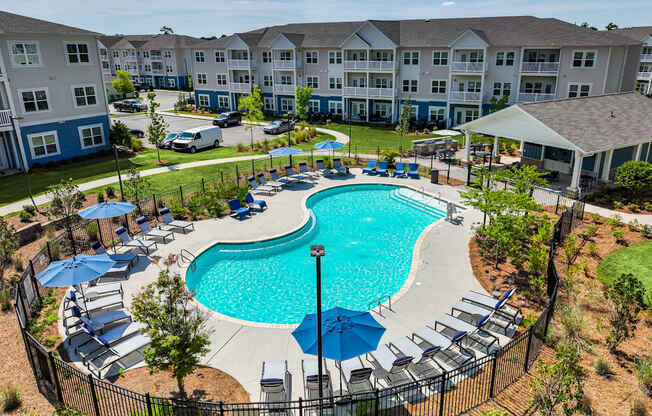 A large swimming pool surrounded by a black fence and lounge chairs.