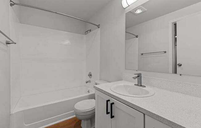 A white bathroom with a toilet, sink, and bathtub.