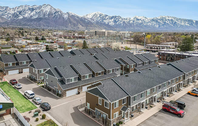 A large building complex with a parking lot in front and snow-capped mountains in the background.