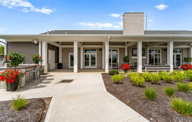 A building with a covered walkway and flower beds in front.