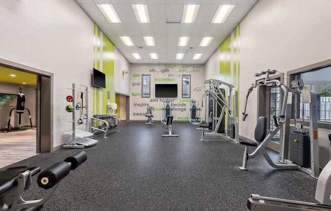 A gym with a variety of equipment including treadmills, weights, and exercise machines.