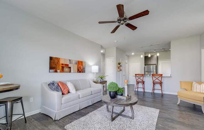 A living room with a white couch, a coffee table, and a ceiling fan.