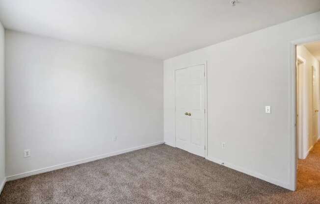 A room with a carpeted floor and a white door.