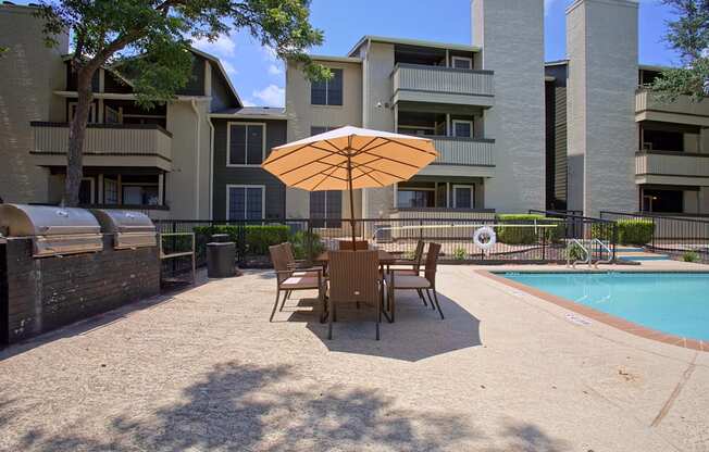 A patio with a table and chairs and an umbrella.