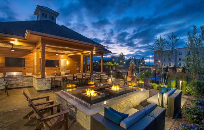 a patio with a seating area and a fire pit at night