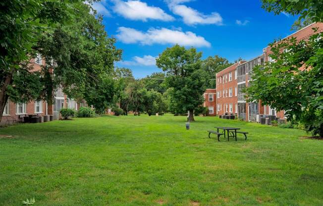 a green lawn with a picnic table in front of a brick building