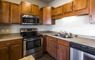 an empty kitchen with wooden cabinets and stainless steel appliances