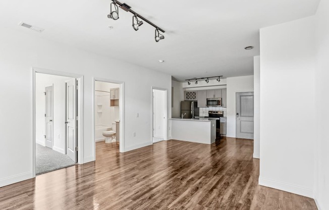 a living room and kitchen with white walls and wood floors