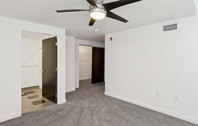 A room with a ceiling fan and carpeted floor.