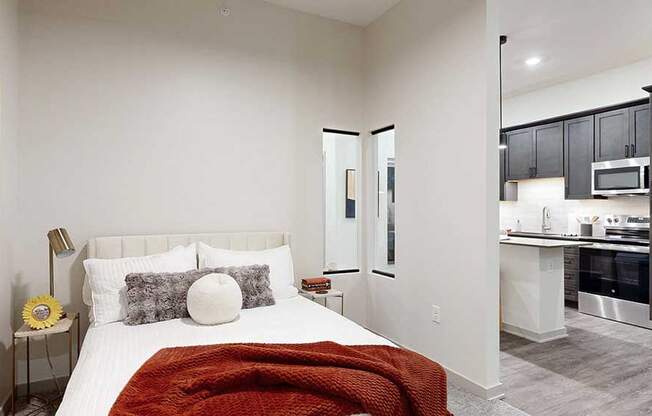 a bed with a red throw blanket and neutral-toned walls