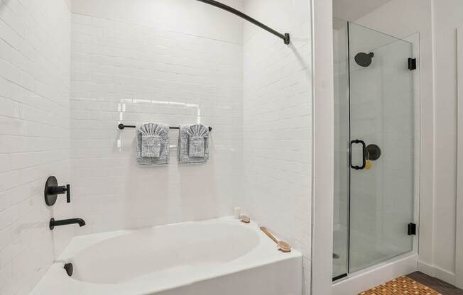 A white bathroom with a white tub and a glass shower door.
