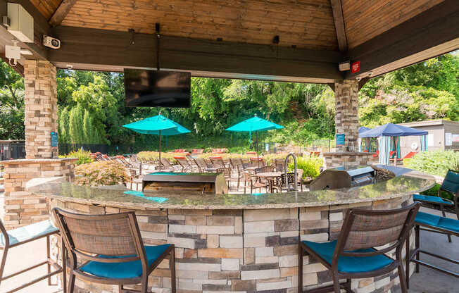 A patio with a bar and chairs under a roof.