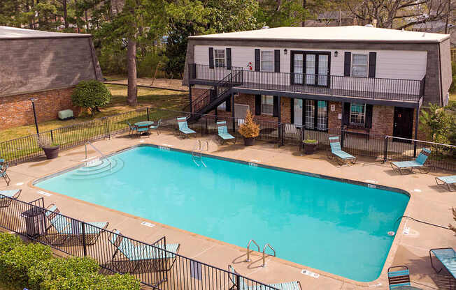 A small pool surrounded by a black fence and chairs.
