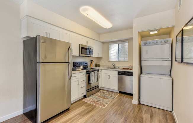 Kitchen with Washer/Dryer , Hardwood Inspired Floor, Refrigerator and White Cabinets at Silverstone Apartments, Davis