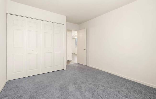 A room with white walls and a grey carpet.