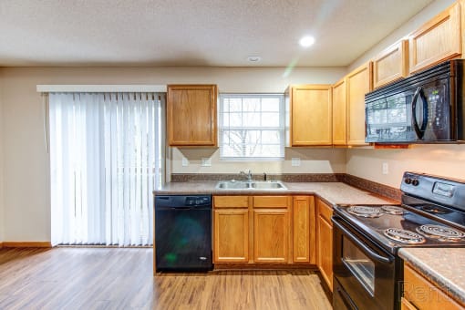 a kitchen with wooden cabinets and appliances and a window