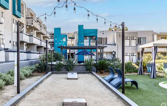 a courtyard with a pool and chairs and a blue building