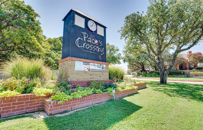 a garden with a clock tower on top of a brick wall